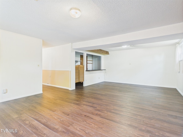 unfurnished living room featuring baseboards, a textured ceiling, and wood finished floors