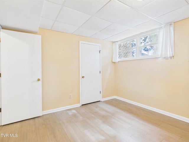 interior space featuring baseboards, a paneled ceiling, and wood finished floors