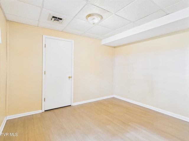 spare room featuring baseboards, visible vents, a paneled ceiling, and light wood finished floors