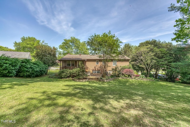 rear view of house featuring a yard and brick siding