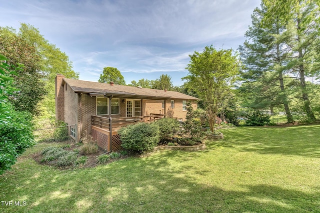 view of property exterior featuring a chimney, a wooden deck, brick siding, fence, and a yard