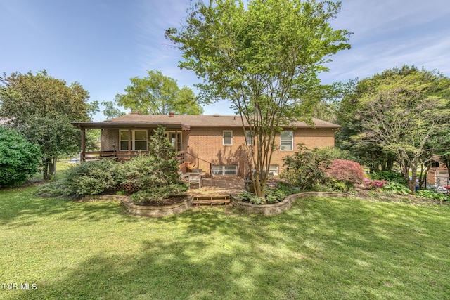back of property with a wooden deck, a yard, and brick siding
