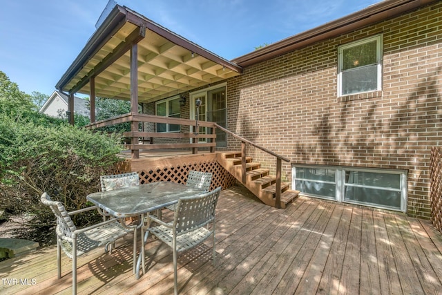 wooden terrace with outdoor dining area and stairs
