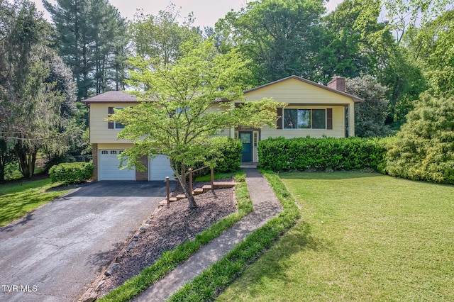 raised ranch with a garage, a front lawn, a chimney, brick siding, and driveway