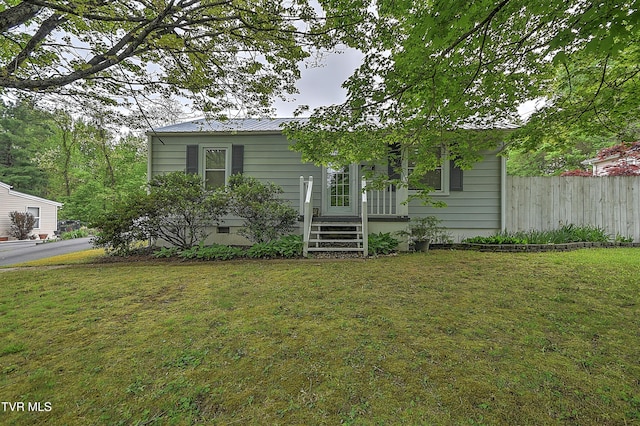 view of front of property with fence, metal roof, and a front yard