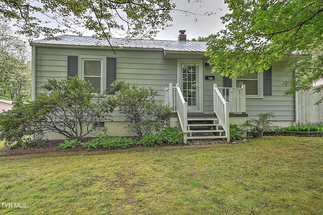 view of front of home with a front lawn, a chimney, and metal roof