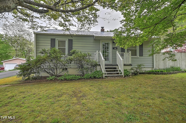 single story home with a garage, fence, a front yard, a chimney, and metal roof