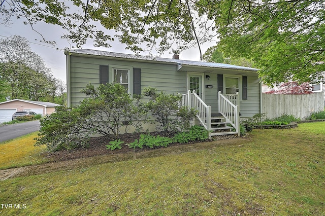 view of front of home with a garage, fence, metal roof, and a front lawn