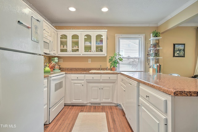kitchen with ornamental molding, a sink, a peninsula, and white appliances