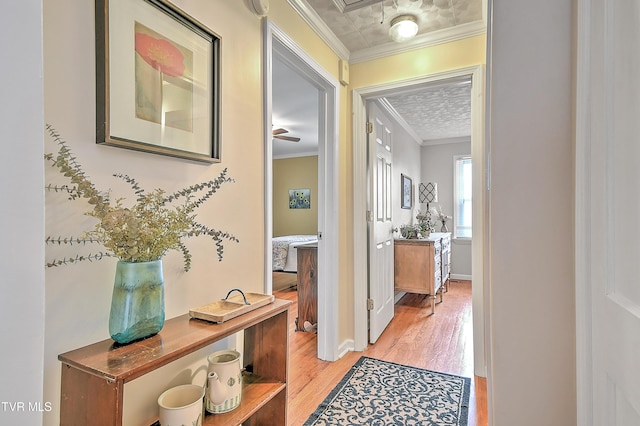 hallway featuring light wood-style floors, ornamental molding, and baseboards