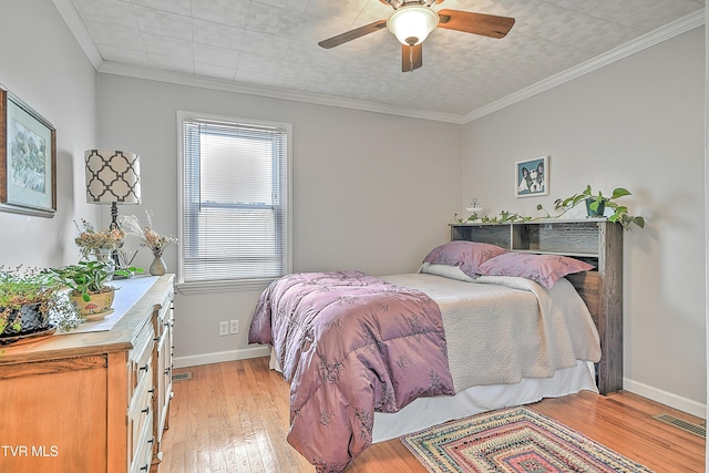 bedroom featuring ceiling fan, visible vents, light wood-type flooring, baseboards, and ornamental molding