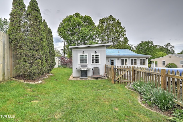 back of house featuring a lawn, a fenced backyard, and metal roof
