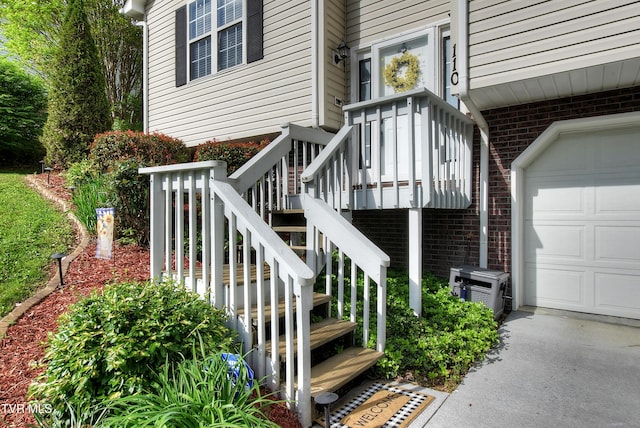 entrance to property featuring brick siding, driveway, and a garage