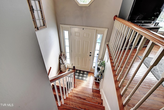 entryway with stairway, a healthy amount of sunlight, hardwood / wood-style floors, and a towering ceiling