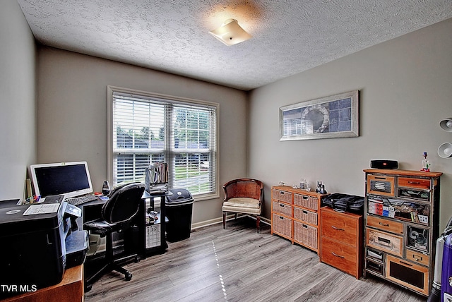 office space with baseboards, light wood-type flooring, and a textured ceiling