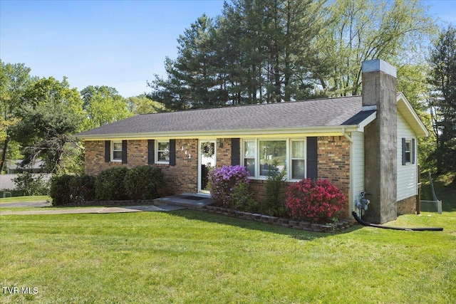 single story home with brick siding, a chimney, and a front yard