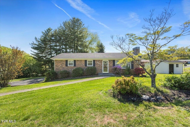 ranch-style house featuring brick siding, an outdoor structure, and a front yard