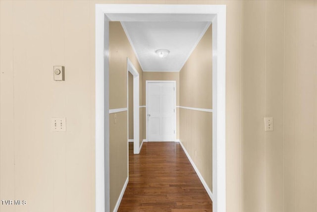 corridor with baseboards, ornamental molding, and dark wood-style flooring