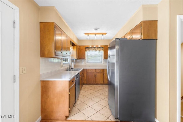 kitchen with light countertops, brown cabinets, tasteful backsplash, a sink, and stainless steel appliances