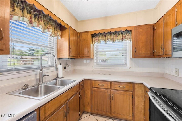 kitchen with light countertops, brown cabinets, a sink, backsplash, and stainless steel appliances