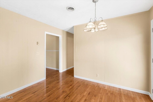 unfurnished room featuring an inviting chandelier, baseboards, light wood-style flooring, and visible vents