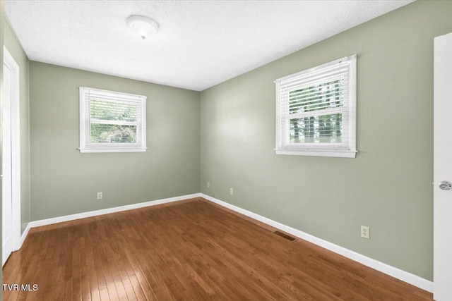 unfurnished room with baseboards, visible vents, and wood finished floors