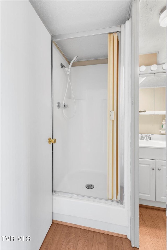 full bath featuring a shower stall, wood finished floors, and vanity