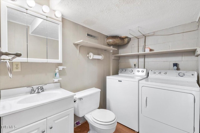 bathroom with wood finished floors, a textured ceiling, and washer and dryer
