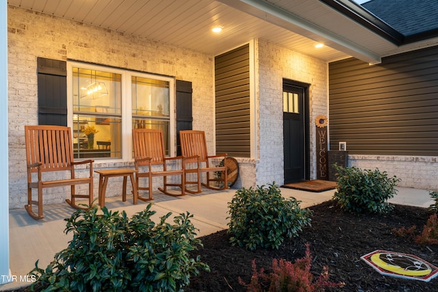 entrance to property with covered porch and brick siding