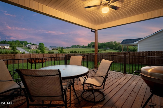 wooden terrace featuring a fenced backyard, outdoor dining space, ceiling fan, and a yard