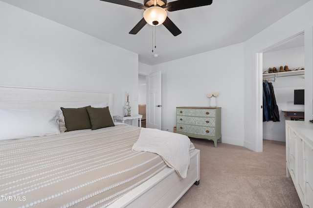 bedroom with a closet, light carpet, baseboards, a spacious closet, and a ceiling fan