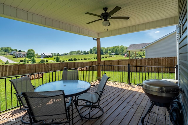 wooden terrace featuring grilling area, a fenced backyard, a ceiling fan, a lawn, and outdoor dining space