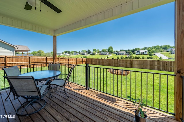 wooden deck with a fenced backyard, outdoor dining area, ceiling fan, and a lawn