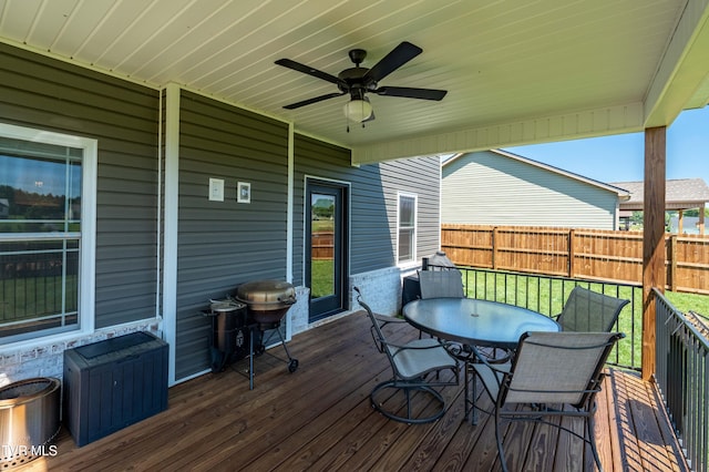 wooden terrace featuring a fenced backyard, outdoor dining space, and ceiling fan