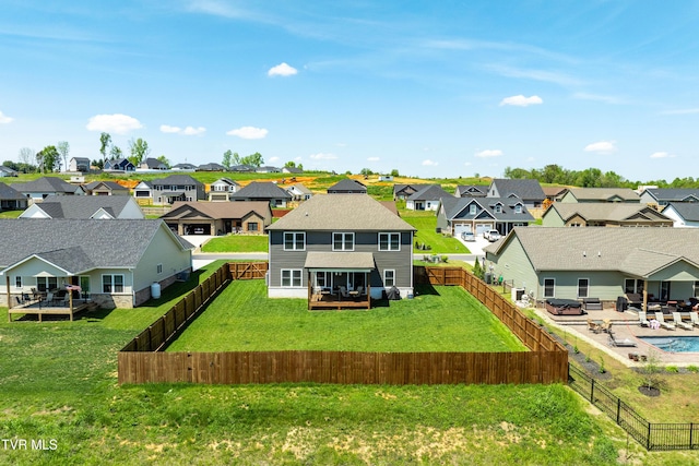 back of property featuring a fenced backyard, a yard, and a residential view