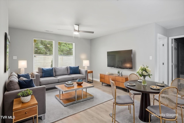 living area with light wood-type flooring, baseboards, ceiling fan, and visible vents