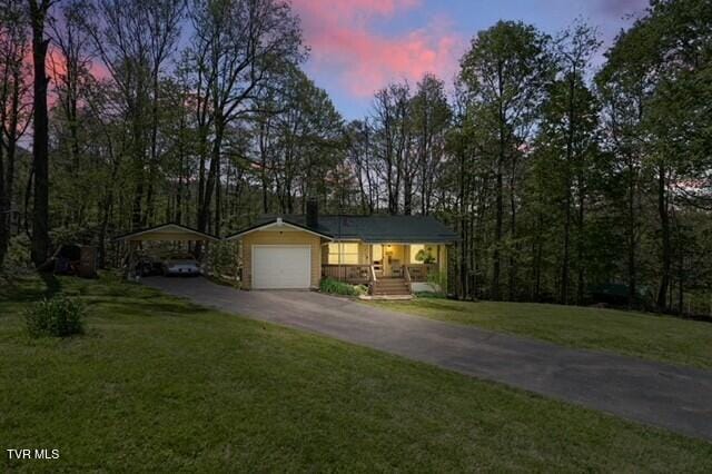 368 Burbank Rd, Roan Mountain, TN 37687 - view of front facade featuring a lawn, an attached garage, a detached carport, and aphalt driveway