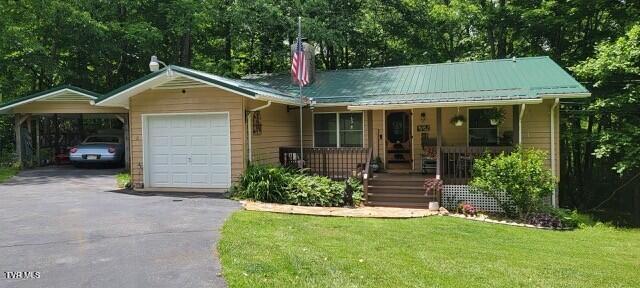 368 Burbank Rd, Roan Mountain, TN 37687 - view of front of house with a porch, asphalt driveway, a front lawn, an attached garage, and metal roof