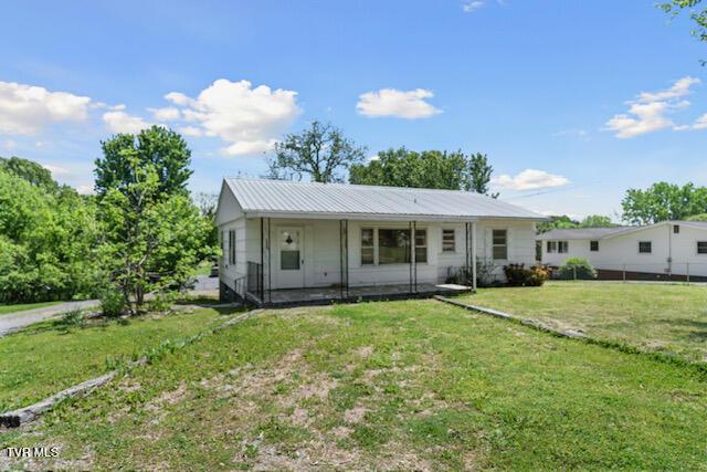 view of front of house featuring a front lawn and metal roof