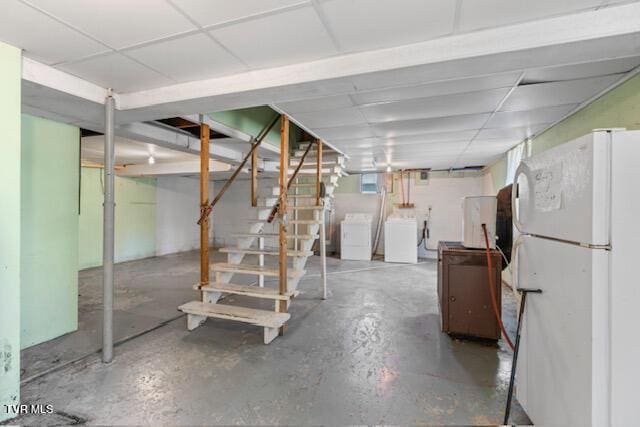 basement with freestanding refrigerator, a paneled ceiling, stairs, and washing machine and clothes dryer