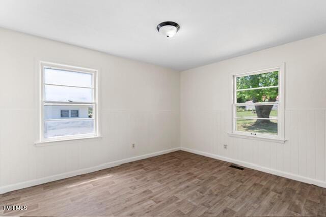 unfurnished room featuring baseboards, wood finished floors, and visible vents