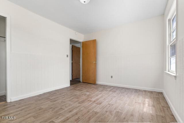 unfurnished bedroom featuring baseboards, wainscoting, and wood finished floors