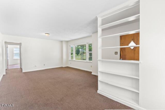 unfurnished living room featuring baseboards and carpet flooring