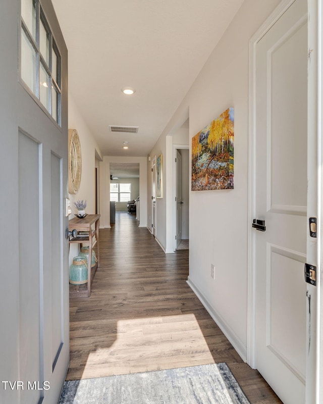 hallway featuring visible vents, recessed lighting, baseboards, and wood finished floors