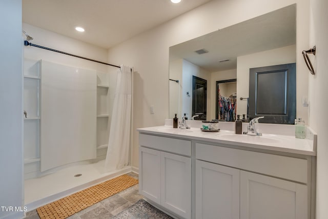 bathroom featuring a sink, double vanity, curtained shower, and a spacious closet