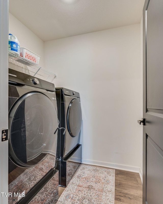laundry room with baseboards, laundry area, wood finished floors, and washer and dryer
