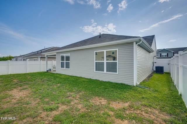 rear view of property featuring a yard, cooling unit, and a fenced backyard