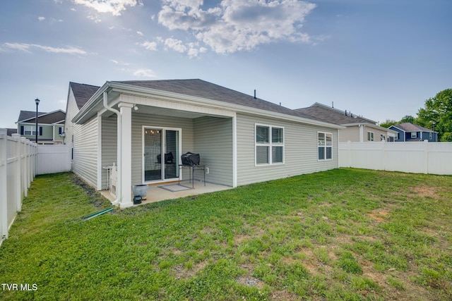 back of house featuring a lawn, a fenced backyard, and a patio area