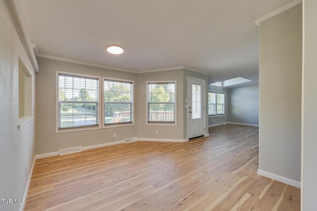 spare room featuring visible vents, light wood finished floors, crown molding, and baseboards