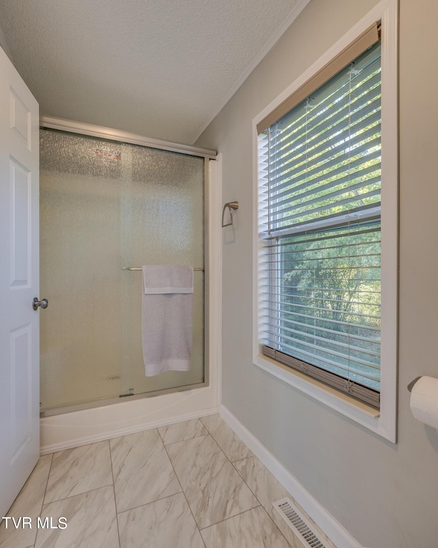 full bathroom featuring visible vents, a shower with shower door, a textured ceiling, and marble finish floor